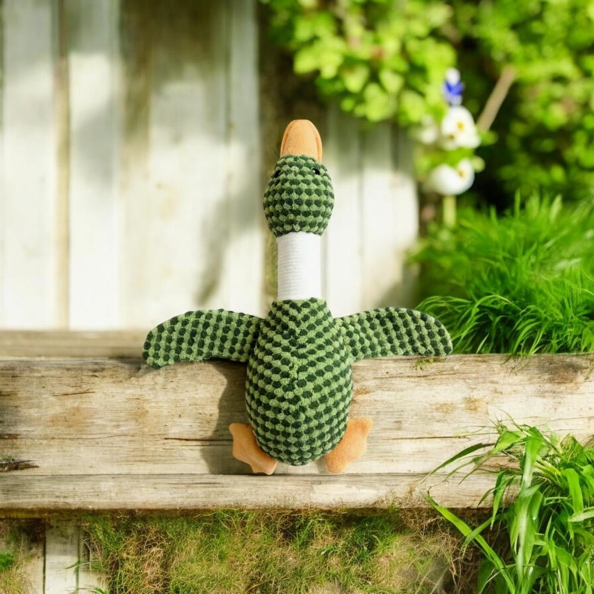 Green and black checkered duck toy on a wooden bench outdoors