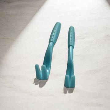 Two blue plastic hooks on a light wooden surface