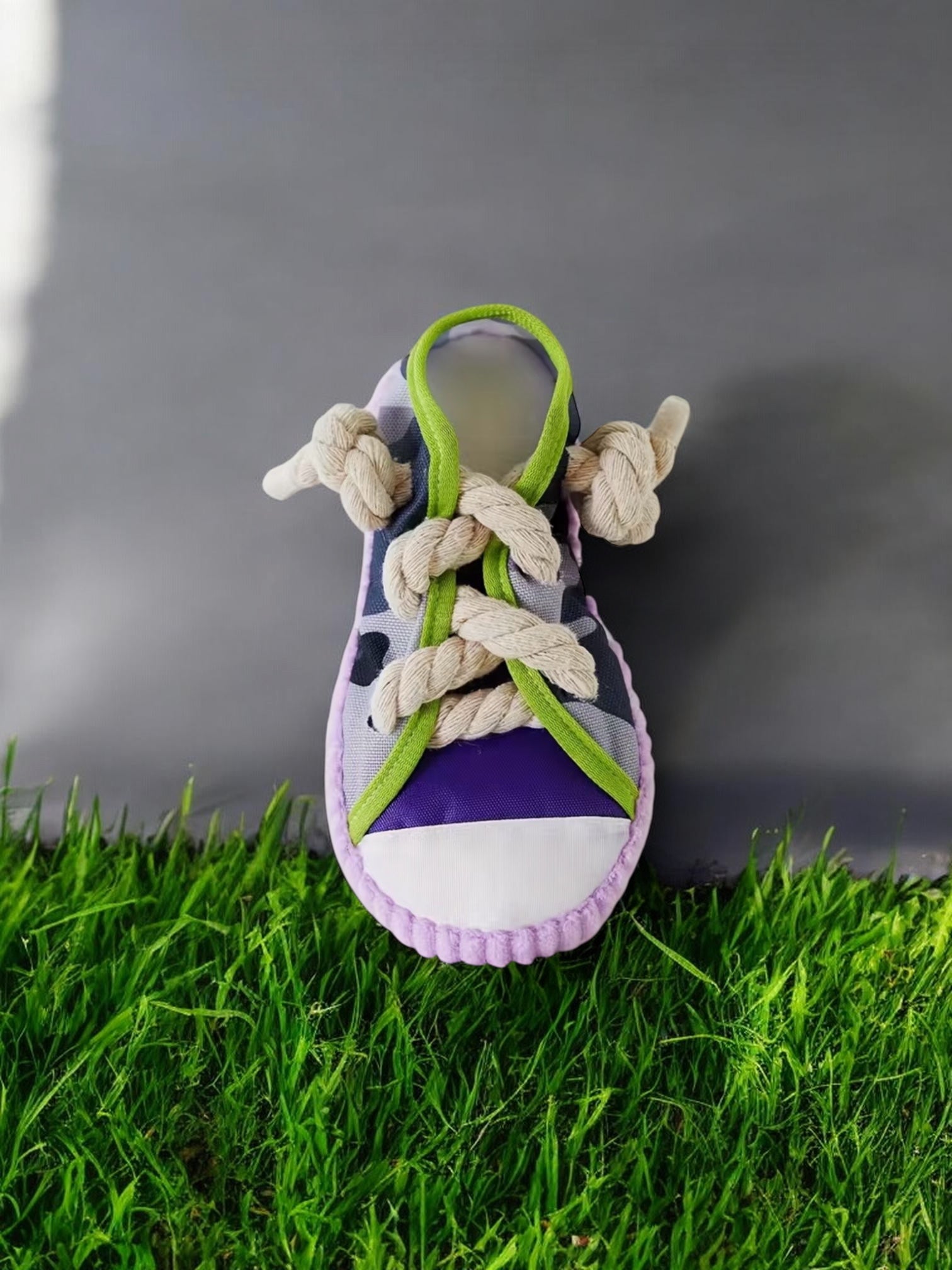 Baby shoe with purple sole and green laces on grass