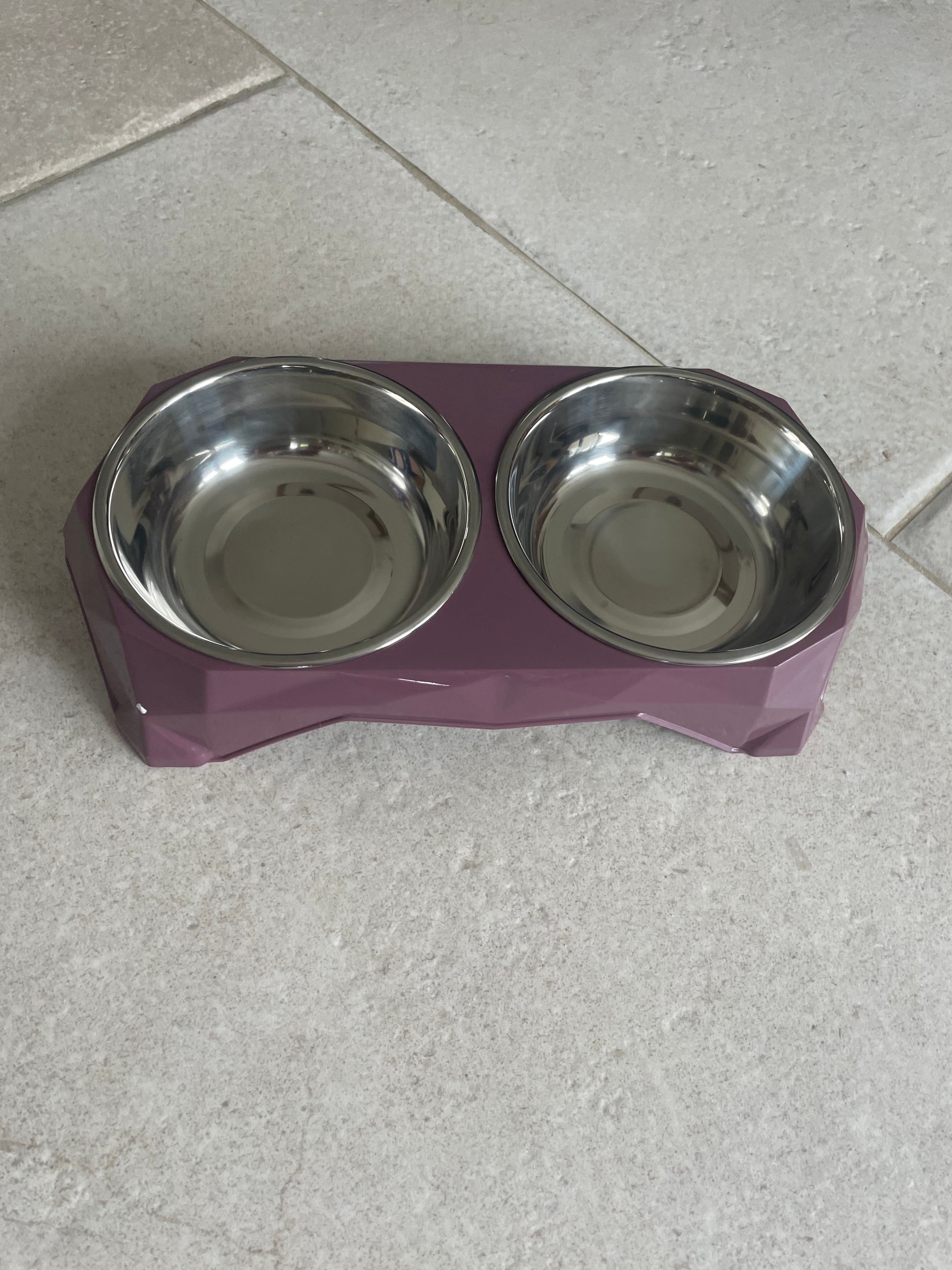 Purple pet feeder with two silver bowls on a tiled floor