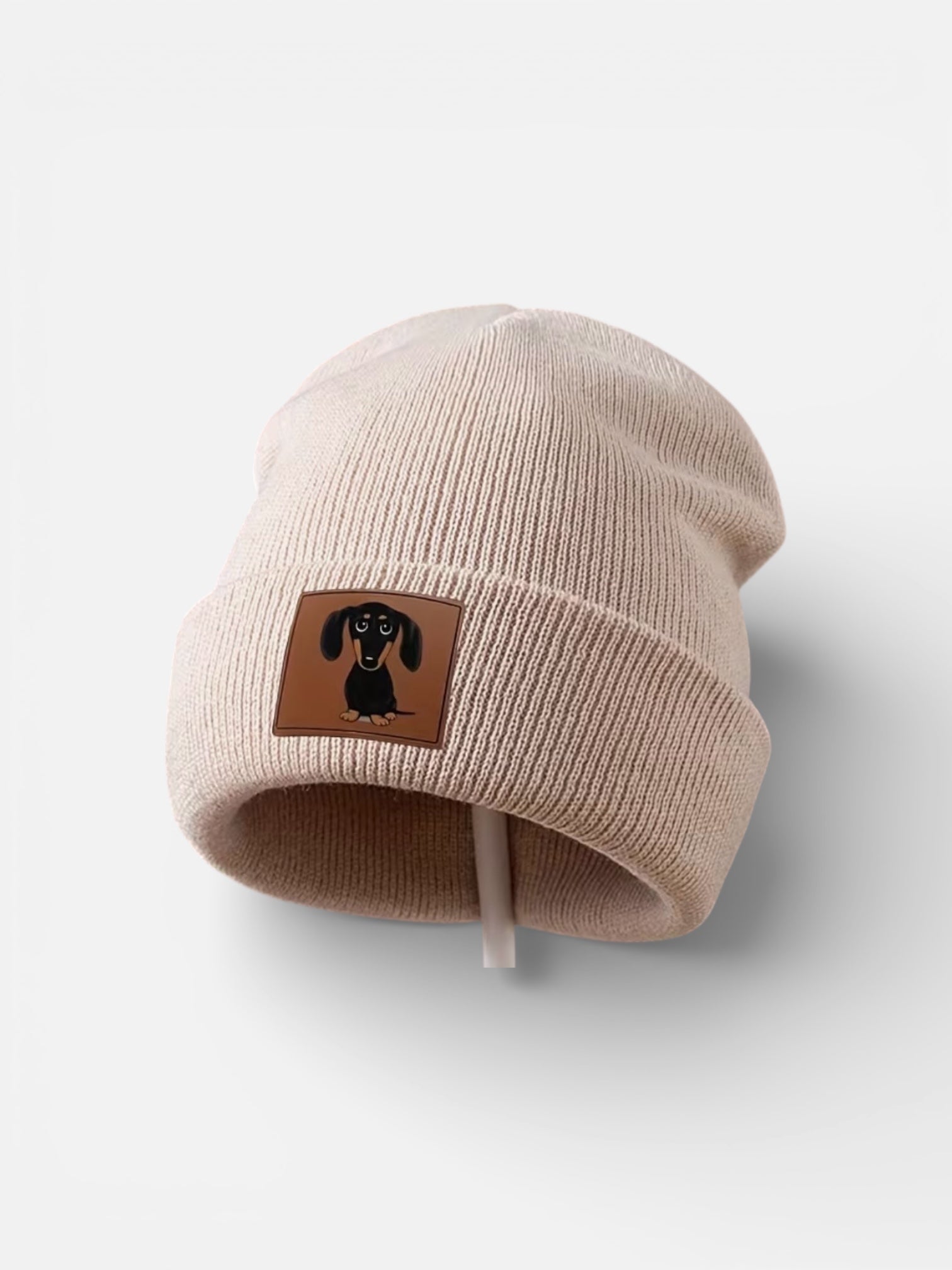 Beige beanie with a brown patch featuring a dachshund on a light gray background
