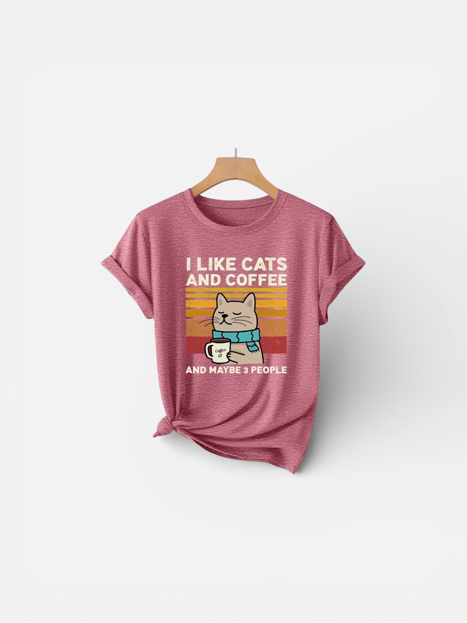 Pink t-shirt with a graphic of a cat holding a coffee cup and text 'I like cats and coffee and maybe 3 people' on a white background.