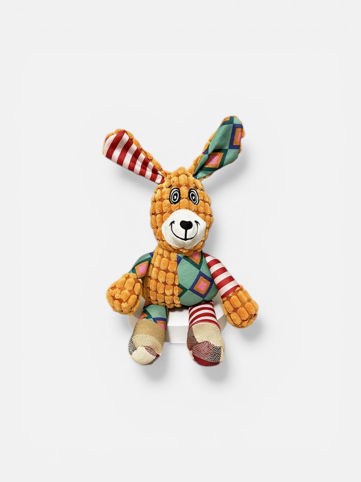 Colorful toy rabbit with a striped scarf on a white background