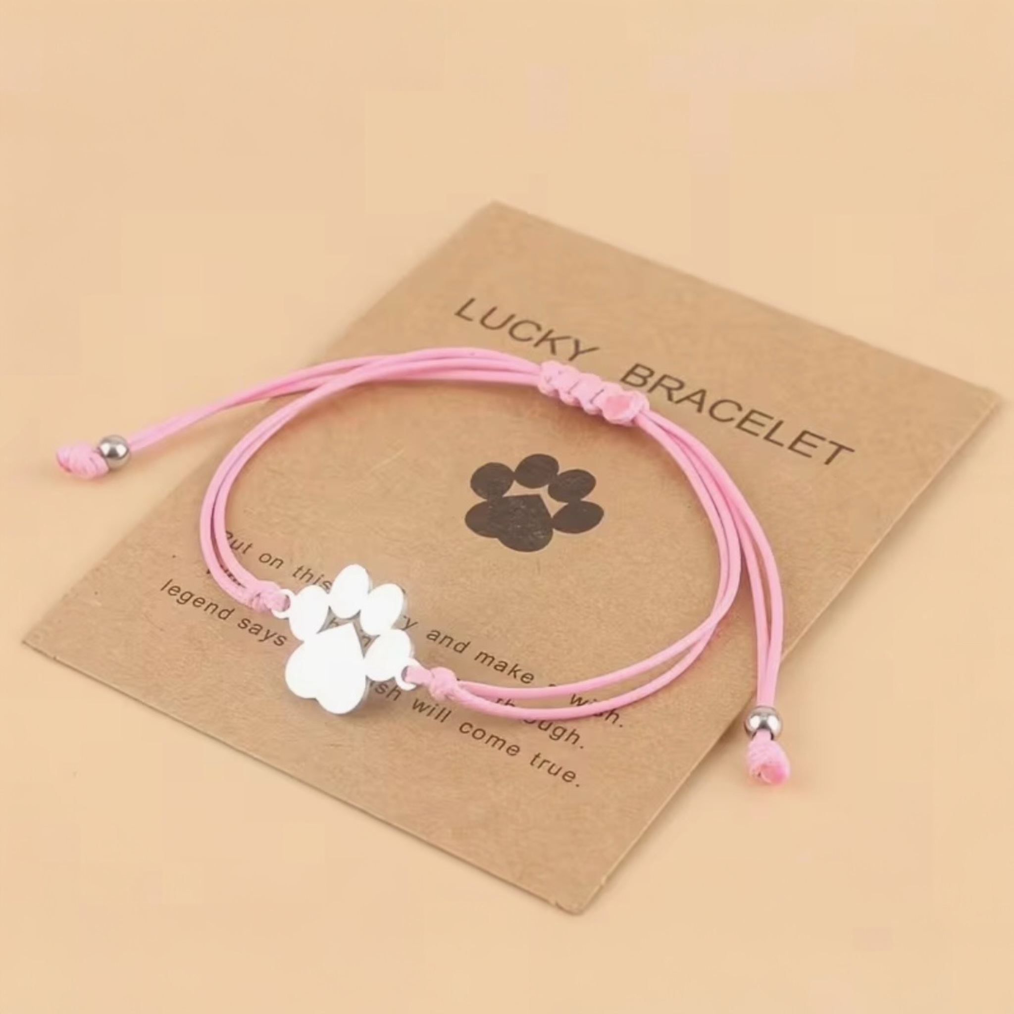 Pink bracelet with paw charm on a brown card