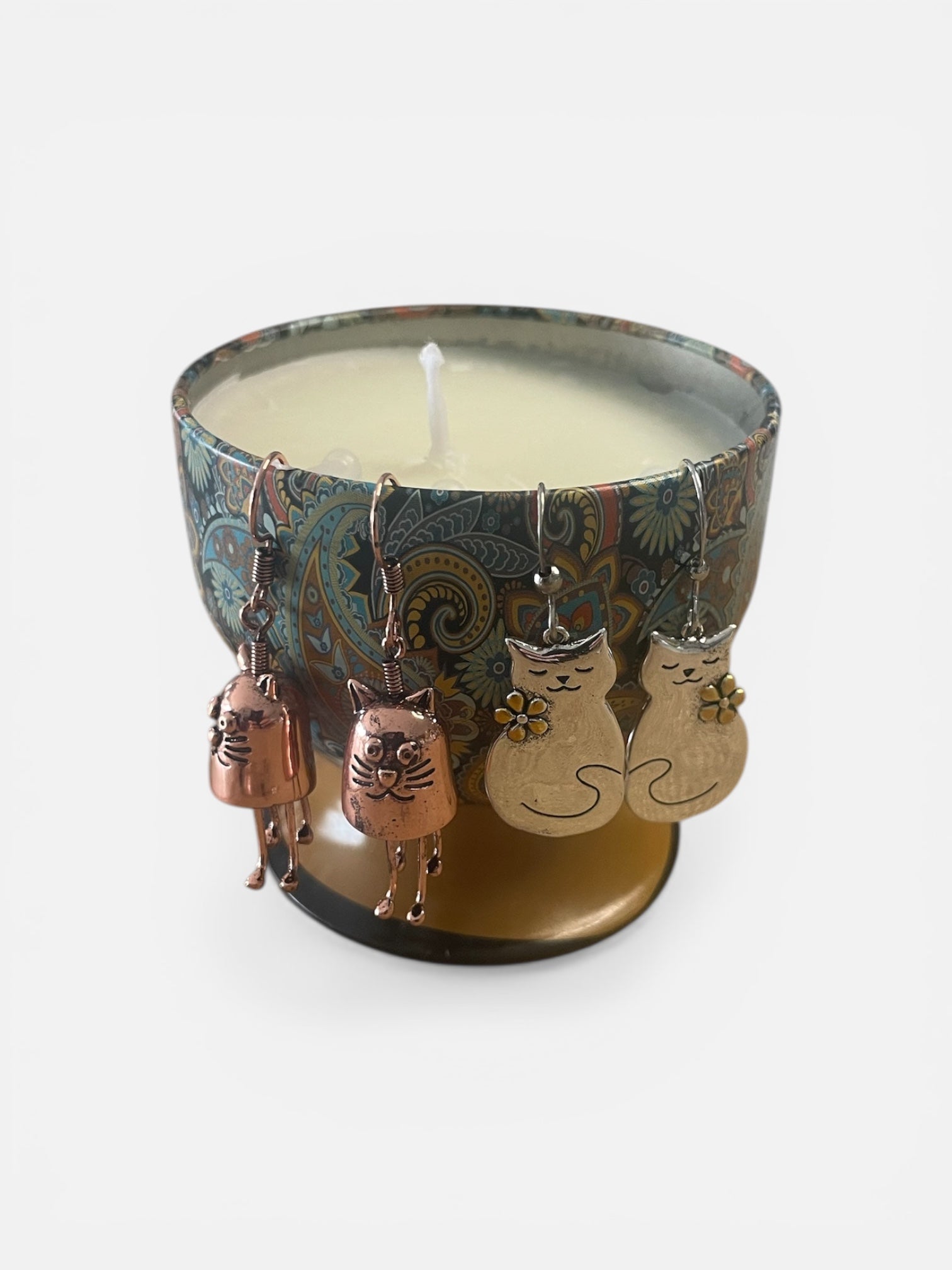 Candle with cat-themed metal charms on a white background