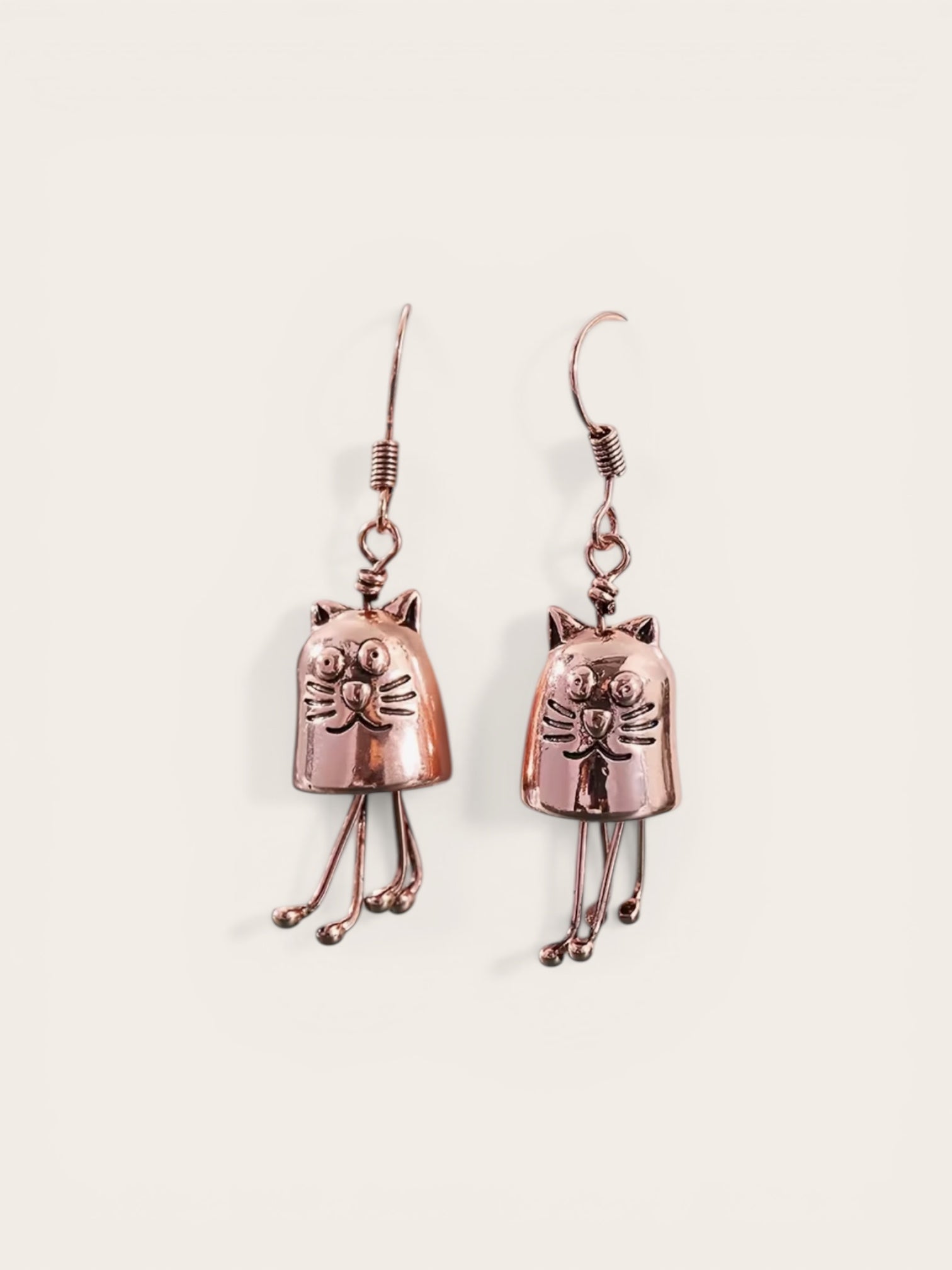 Copper cat-shaped earrings on a light beige background
