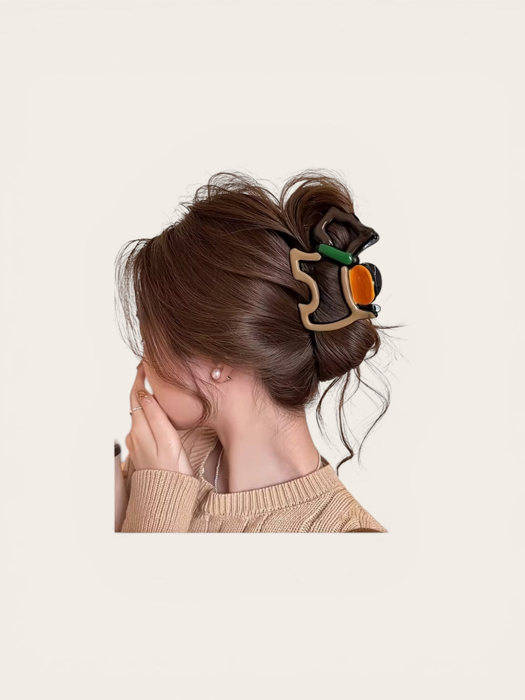 Person with brown hair styled in an updo using a decorative hair clip on a beige background